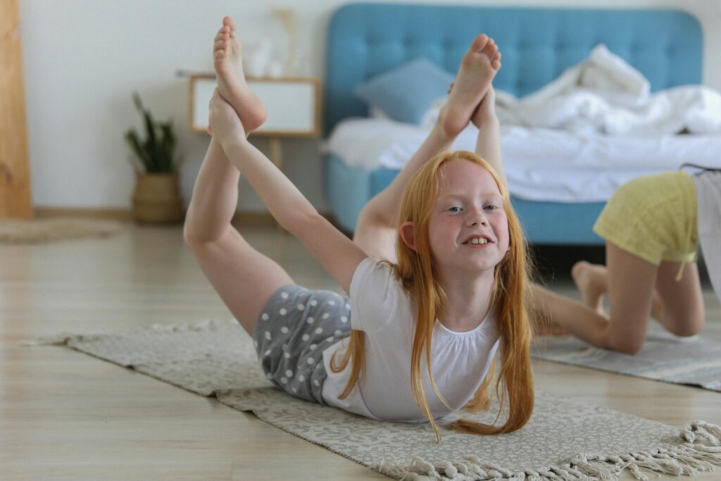 pexels-photo-5063292-5063292 Full body of cheerful girl in casual clothing with reddish hair looking away with smile while stretching legs on carpet in bright cozy living room on blurred background